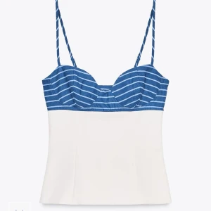 Randig blå och vit populärt linne  - Säljer en snygg topp med smala axelband. Överdelen är blå med vita ränder och nedre delen är helt vit. Toppen har en markerad byst och dragkedja i sidan för enkel påklädning. Perfekt till sommarens alla looks! SLUTSÅLD PÅ HEMSIDAN. Prislapp kvar tyvärr för liten.