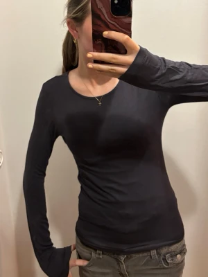 grå långärmad topp  - Säljer en enkel och stilren grå långärmad ”soft touch” topp med rund hals. Toppen är figurnära och gjord i mjukt bomullsmaterial, perfekt att matcha med jeans eller kjol. Passar dig som gillar en clean och klassisk look.