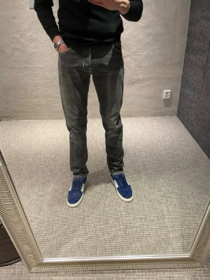 Grå jeans från Jacob Cohën, storlek 32 - Säljer ett par grå jeans från Jacob Cohën i storlek 32. De har klassisk femficksdesign, raka ben och snygga slitningar för en avslappnad look. Jeansen är tillverkade i mjukt bomullsmaterial och har vita kontrastsömmar som ger extra detaljer. Ny pris 5200kr