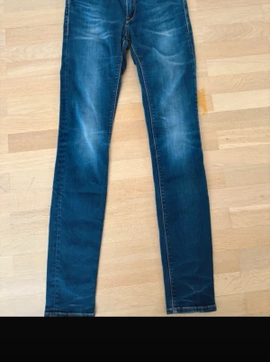 Blå Replay jeans, skinny fit, stl 28 - Säljer ett par blå skinny jeans från Replay i storlek 28. Jeansen har klassisk femficksdesign, snygga slitningar och Replay-logga på fickan. De är tillverkade i stretchigt jeansmaterial för en tight och bekväm passform. 