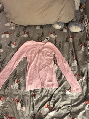 Ljusrosa ribbad långärmad topp Cubus - Supersöt ljusrosa långärmad topp från Cubus i ribbad bomull. Rund halsringning och tre knappar framtill ger en chill och enkel look. Perfekt till jeans eller mjukisbyxor för en avslappnad vibe.