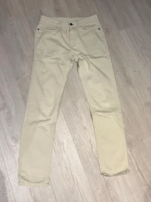 Beiga chinos med rak passform - Snygga beiga chinos med klassisk rak passform och fem fickor. Byxorna har knapp och dragkedja framtill samt bälteshällor. Perfekta för en clean och stilren look, tillverkade i mjukt bomullsmaterial som är skönt att bära hela dagen.