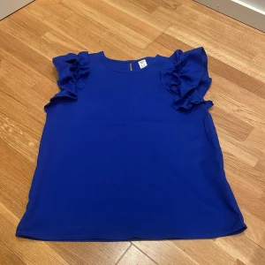 Kornblå blus med volangärmar - Snygg kornblå blus från SHEIN med volangdetaljer på ärmarna och rund halsringning. Blusen har en knapp i nacken för enkel påklädning.