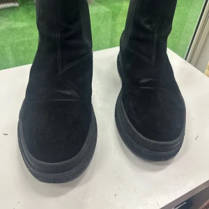 Svarta chelsea boots från Gant i mocka 46 - Säljer ett par svarta chelsea boots från Gant i mjuk mocka med elastiska paneler på sidorna och dragflikar både fram och bak. Skorna har rund tå och platt sula, perfekta till höst och vinter. Insidan är fodrad i skinn för extra komfort.