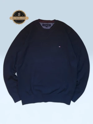 mörkblå stickad tröja Tommy Hilfiger - Klassisk mörkblå stickad tröja från Tommy Hilfiger med rund hals och diskret logga broderad på bröstet. Tröjan har ribbade muddar vid ärmslut och nederkant, vilket ger en snygg passform. Perfekt till höst och vinter för en clean och stilren look.