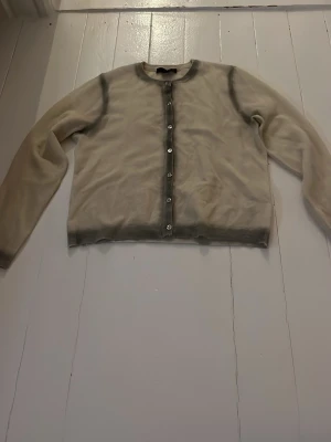 Beige kofta från Zara med knappar - Säljer en beige kofta från Zara med gråtonade kanter och pärlemorknappar framtill. Koftan har rund halsringning och är långärmad. Super fin💓liten i storleken så därför i storlek M