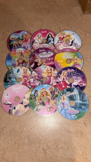Barbie DVD-samling - Upptäck magiska äventyr med denna samling Barbie-filmer! Perfekt för dig som älskar sagor, prinsessor och fantasifulla världar. Filmerna bjuder på spännande berättelser, vackra animationer och inspirerande karaktärer. En färgsprakande samling för alla unga filmälskare! 12 stycken dvd skivor (endast som skivor). Väldigt repiga men funkar sådär, de kan stanna ibland men ”funkar” ändå måste ha tålamod bara. Kommer ENDAST som skivor alltså utan fodral & alla är på svenska.