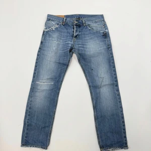 Dondup jeans - Säljer ett par ljusblå jeans med raka ben och slitna detaljer vid fickor och knän. Jeansen har fransade benslut och klassisk femficksdesign. Materialet är jeans i bomull och passformen är normal. Perfekta för en avslappnad look. Naturliga slitningar och håll direkt från fabriken vilket är jätte efterfrågat!