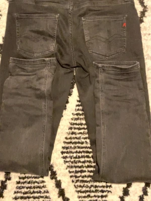 Svarta Replay jeans - Säljer ett par svarta Replay jeans i klassisk femficksmodell. Jeansen har raka ben, normal passform och är tillverkade i ett mjukt bomullsmaterial med lite stretch. Snygga detaljer med Replay-logga på fickan och metallknapp framtill.