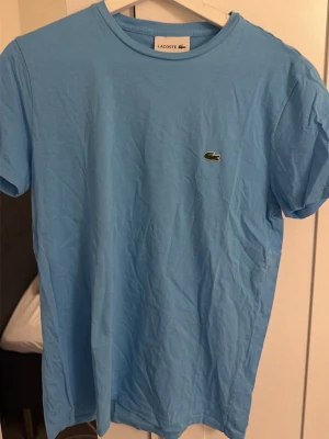 Ljusblå t-shirt från Lacoste - Säljer en ljusblå t-shirt från Lacoste storlek m men passar även S