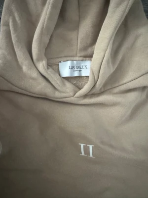 Hoodie - Beige hoodie från Les Deux med diskret II-logga på bröstet. Mjuk och bekväm med huva och magficka. Sparsamt använd och i fint skick utan synliga defekter. Passar perfekt till vardags. Både för män och kvinna, det är storlek 158/164