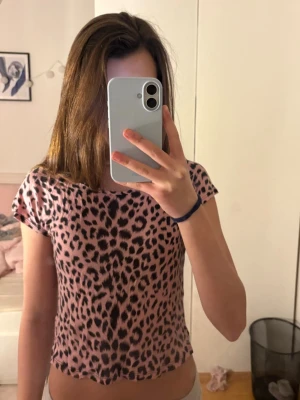 Leopardmönstrad topp från Forever 21 - Säljer en rosa leopardmönstrad topp från Forever 21. T-shirten är croppad med korta ärmar och har en figurnära passform. Materialet är mjukt och stretchigt.