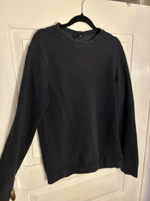Mörkblå sweatshirt från H&M Basic - En enkel och stilren mörkblå sweatshirt från H&M Basic. Tröjan har rund halsringning, långa ärmar och mjukt material i bomullsblandning. Perfekt för chill dagar eller när du vill ha en clean look.