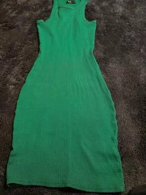 Grön ribbad klänning från FB Sister - Snygg grön ribbad klänning från FB Sister i storlek XS. Klänningen är ärmlös och har en kroppsnära passform med rund halsringning. Perfekt för dig som gillar enkla och stilrena plagg med lite edge.