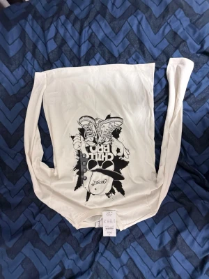 Vit långärmad t-shirt Chill Bro - Säljer en vit långärmad t-shirt från Chill Bro med svart streetinspirerat tryck av sneakers, keps och solglasögon på framsidan. Skön passform och tillverkad i mjuk bomull, perfekt för en avslappnad och cool stil.