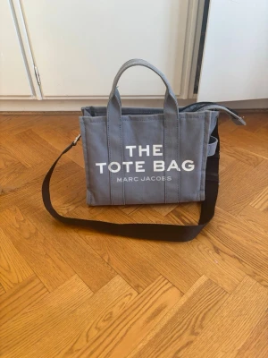 Blå Tote bag från Marc Jacobs  - Säljer en medelstor tote bag från Marc Jacobs. Den är lite sliten men har inga stött slitage. Det finns band till och är jättebra.