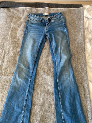 Blå bootcut jeans från Zara, strl 32 - Säljer ett par blå bootcut jeans från Zara i storlek 32. Jeansen har klassisk femficksdesign, normal passform upptill och utsvängda ben. Tillverkade i mjukt denimtyg som ger en avslappnad vibe. Perfekta till sneakers eller boots.