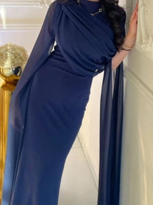 Marinblå långklänning med drapering - Elegant marinblå långklänning med draperad överdel och långa, transparenta ärmar. Klänningen har en smickrande, figurnära passform och hög halsringning. Perfekt för dig som vill ha en stilren och sofistikerad look. 