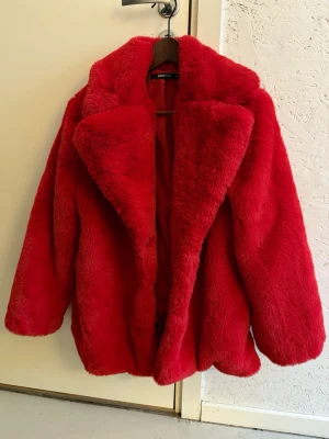 Röd pälsjacka från Gina Tricot - Fluffig och oversized röd pälsjacka från Gina Tricot i storlek 36. Aldrig använd. Jackan har bred krage, helröd insida och har en mjuk känsla. Perfekt statement-plagg för dig som vill sticka ut och hålla dig varm under kyliga dagar. 
