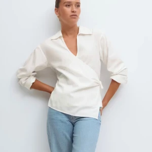 Vit omlottblus  - Snygg vit omlottblus från Gina tricot  med knyt i sidan och v-ringad krage. Långärmad modell med avslappnad passform och klassisk krage. Jag har aldrig använt den, slutsåld på hemsidan💕