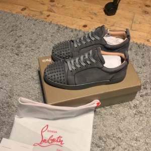 Grå Christian Louboutin  - Säljer ett par gråa sneakers från Christian Louboutin. Skorna har snörning och en låg profil, perfekt för dig som vill sticka ut med exklusiv streetstyle. Skorna är använda 2 gånger och är i perfekt skick. Pris går att diskutera vid snabbare affär.  