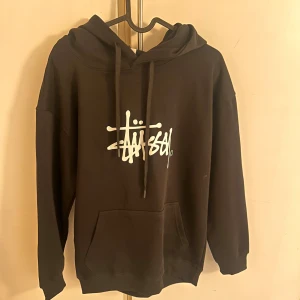  Stüssy hoodie  - Svart hoodie från Stüssy med vit logotyp på bröstet och tryck på huvan. Ny pris ligger på ca 1400kr men säljer endast för 400kr!