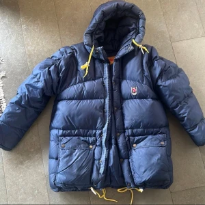 Fjällräven dunjacka xxs - Mycket fint skick. Inga hål eller fel utöver att läderlapparna vid hakans dragskro är aningen skavda- se bild. Fluffig och varm. Mörkblå. Passar xs-m.