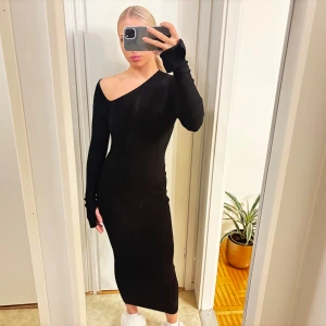 Svart oneshoulder långklänning - Säljer en svart ribbad långklänning med oneshoulder och lång ärm. Klänningen har en tight passform och är i storlek S