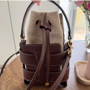 Brun H&M Väska  - Snygg super trendig brun handväska från HM. Väskan har coola detaljer med synliga sömmar och snörning upptill, samt både handtag och axelrem i skinn. Perfekt storlek för det viktigaste och ger en trendig touch till din outfit.