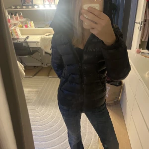 Svart Moncler pufferjacka med huva - Säljer en svart pufferjacka från Moncler med huva och dragkedja framtill. Jackan har en snygg, quiltad design och är perfekt för kalla dagar. Den är lätt och har en stilren look som funkar till jeans och sneakers. Moncler-logga finns på insidan. Och på sidan av armen! Skriv för frågor, pris kan diskuteras.