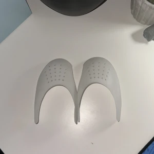 Vita crease skydd NO SIZE - Säljer ett par vita crease skydd för sneakers, perfekta för att hålla formen på dina skor. De är gjorda i mjuk syntet med små hål för ventilation och passar de flesta sneakers. Enkla att använda och diskreta i skon. Det är NO SIZE och passar alla skor