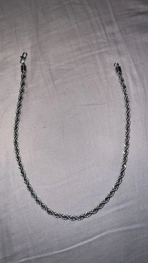 Silverfärgat tvinnat halsband från kejsar - Snyggt halsband i silverfärgad metall med tvinnad kedja och karbinlås. Kedjan har en stilren och modern look som passar perfekt till streetwear eller som layering-piece. Enkel att matcha med andra smycken för en personlig stil.