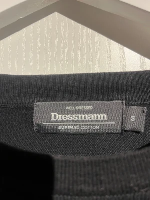 Svart stickad tröja från Dressmann - En stilren svart tröja från Dressmann i mjuk Supima bomull. Tröjan har rund hals, långärmade ärmar och en klassisk passform som funkar till många olika looks. Perfekt för dig som gillar enkla och snygga basplagg. Skick 8/10
