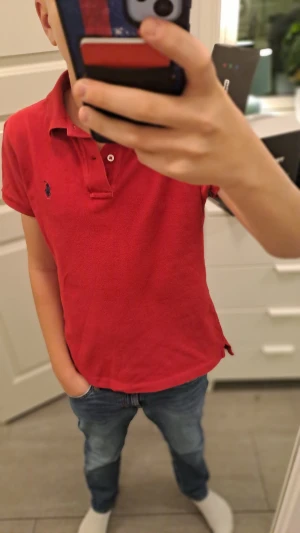 Röd polo från Ralph Lauren xs - Snygg röd pikétröja från Ralph Lauren i storlek xs. Klassisk design med krage, två knappar och den ikoniska blå broderade loggan på bröstet. Tröjan är gjord i mjuk bomull och har en slim passform som sitter riktigt bra. Perfekt för dig som gillar stilrena och tidlösa plagg. Står m på men passar xs. Vid frågor hör av er pris kan diskuteras.