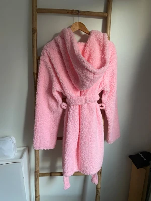 Morgonrock  - Supermysig rosa morgonrock från Boohoo med stor huva och knytbälte i midjan. Långärmade ärmar och fluffigt, mjukt material som ger en chill vibe. Perfekt för dig som vill ha en cozy look och gillar pastellfärger. ALDRIG ANVÄND!🤩