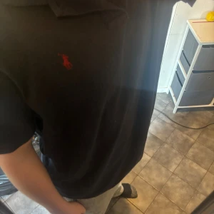 Marnblå ralph lauren piké  - Marinblå t-shirt från Polo Ralph Lauren i klassisk passform, med rött broderat logotyp på bröstet. T-shirten har korta ärmar och är gjord i mjuk bomull som känns skön mot huden. Perfekt för dig som gillar stilrena och ikoniska plagg. Hör gärna av dig vid frågor😊