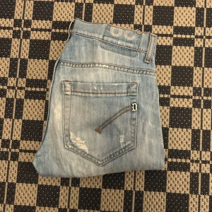 Ljusblå slitna jeans med raka ben - Säljer ett par ljusblå jeans med slitningar och snyggt tvättad look. Jeansen har raka ben, klassiska fem fickor och detaljerade sömmar på bakfickorna. Perfekta för en avslappnad och trendig stil.