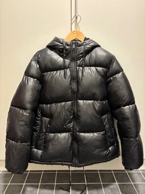 Svart dunjacka med huva - Svart dunjacka med huva och snörning.