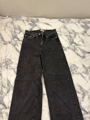 Svarta raka jeans från lager 157  - Snygga svarta jeans från 157 Boulevard med raka ben och klassisk femficksdesign. Jeansen har hög midja, dragkedja och knapp framtill. Perfekta för dig som gillar en enkel och stilren look. Materialet är robust denim i svart tvätt.