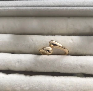 Guldig öppen ring i minimalistisk stil - Snygg och stilren ring i guldton med öppen design och mjuka, organiska former. Perfekt för dig som gillar minimalistiska smycken med en modern twist. Ringen är enkel att matcha med andra accessoarer och ger en trendig touch till din look.