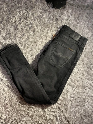 Nudie Jeans - svets  - Snygga svarta Nudie jeans i toppskick säljes!        Inga defekter, sparsamt använda. Skick 10/10 🫨  Jeansen sitter som slimfit/skinny och är riktigt Grisch. Priset kan diskuteras vid snabb affär! Hör av dig om du har frågor eller vill ha fler bilder! 🤝👏