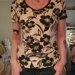 Vit blommig t-shirt med svart tryck - Vit t-shirt med stora svarta blommor och blad.