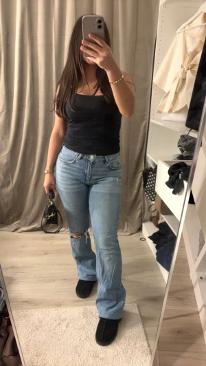 Gina Tricot  ljusblå jeans i bootcut, strl 38 - Snygga ljusblå jeans från Gina tricot i storlek 38. Modellen har bootcut-ben, klassisk femficksdesign och hög midja. Jeansen är i mjukt denim-material och har en liten sliten detalj vid knät för extra edge.