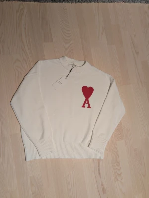 Vit stickad tröja från Ami Paris - Vit stickad tröja från Ami Paris, storlek L. Materialet är mjuk bomull / ull. Helt oanvänd! 