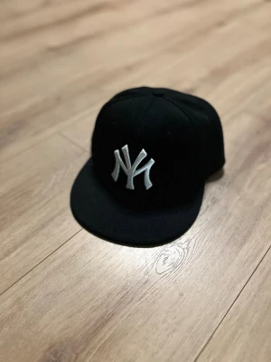  Svart NYC unisex keps -   	•	snapback 	•	NY logo 	•	streetwear 	•	unisex 	•	stilren keps 	•	sportig keps 	•	modeaccessoar 	•	casual stil  Hashtags 	•	#keps 	•	#svartkeps 	•	#NYkeps 	•	#streetwear 	•	#snapback 	•	#fittedcap 	•	#casualstyle 	•	#mode 	•	#unisexfashion 	•	#vintedfind
