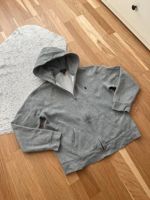 Grå Ralph Lauren Zip Hoodie - Grå Ralph Lauren Zip Hoodie 🤩  Skick: Mycket bra! Nästan inga tecken på användning 🌟 Färg: Grå 🩶 Storlek: XL (18-20) i barnstorlek, passar S i vuxenstorlek 📏  Jag skickar alltid inom 1 dag efter köpet 📬  Jag ser alltid till att förpackningen och köpet hanteras med omsorg och kärlek 😊  Jag rekommenderar dig att köpa! ☺️