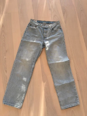 Levi's 501 ljusblå jeans W27 L30 - Säljer ett par klassiska Levi's 501 jeans i ljusblå tvätt. Modellen har rak passform, fem fickor och knappgylf. Jeansen är tillverkade i slitstarkt bomullsmaterial och har den ikoniska läderpatchen bak. Perfekt för en chill och tidlös look.