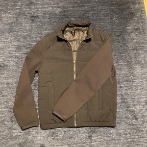 Svart pufferjacka med dragkedja - Snygg svart / mörkblå med hel dragkedja framtill och ståkrage. Jackan har långa ärmar och två sidofickor. Perfekt för kyligare dagar och enkel att matcha med olika outfits.