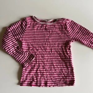 Randig långärmad tröja från H&M - Säljer en långärmad tröja från H&M i rosa med klassiskt horisontellt randigt mönster. Tröjan är i mjuk bomull och har en rund halsringning. Perfekt för dig som gillar färg och enkel stil.