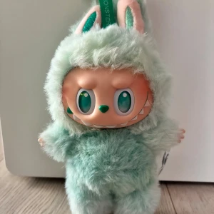 Äkta Labubu - THE MONSTERS Big into Energy Serenity Plush - Söt samlarfigur från POP MARTs THE MONSTERS-serie, modell Serenity. Mjuk plyschdräkt i mintgrönt med stora glittrande ögon och detaljerad design. Levereras med originalförpackning och samlarkort. Helt ny, endast öppnad! Mycket fint skick, perfekt för samlare. Kvitto finns.